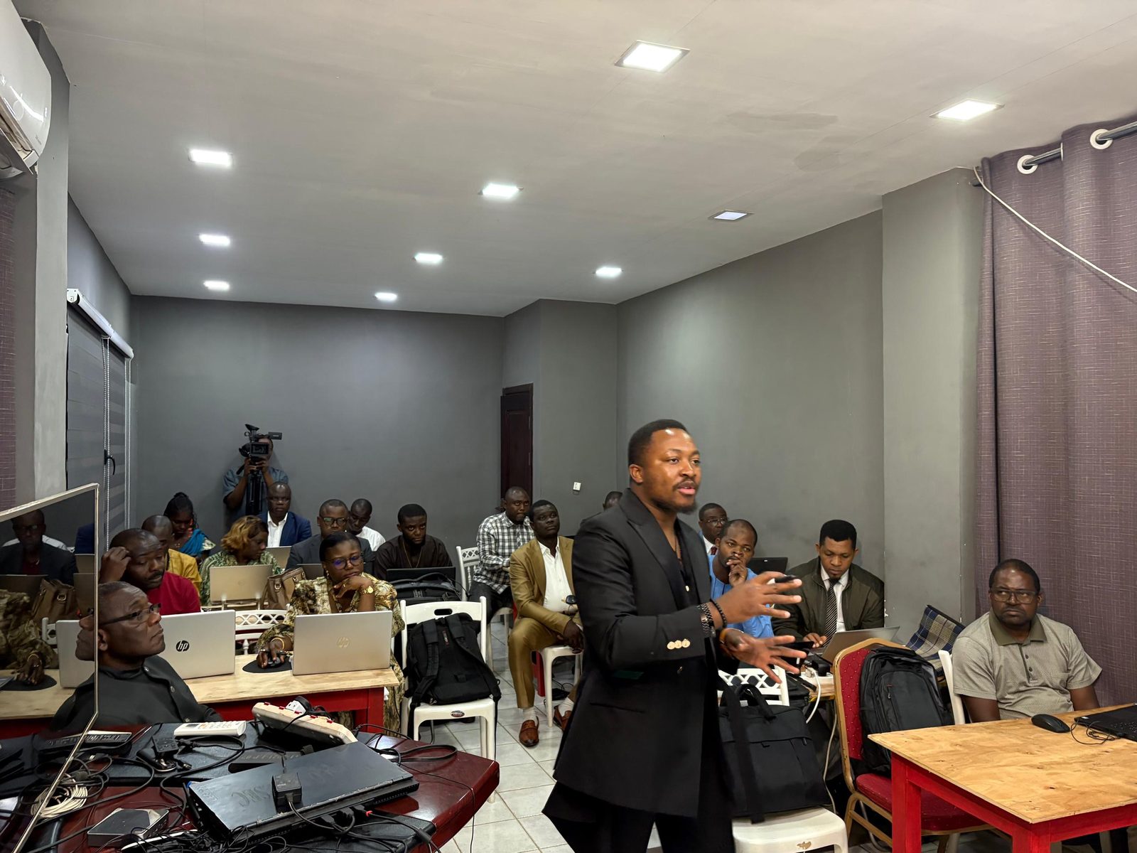 Muluh Godson with the participants. Laptops are open on the tables.
